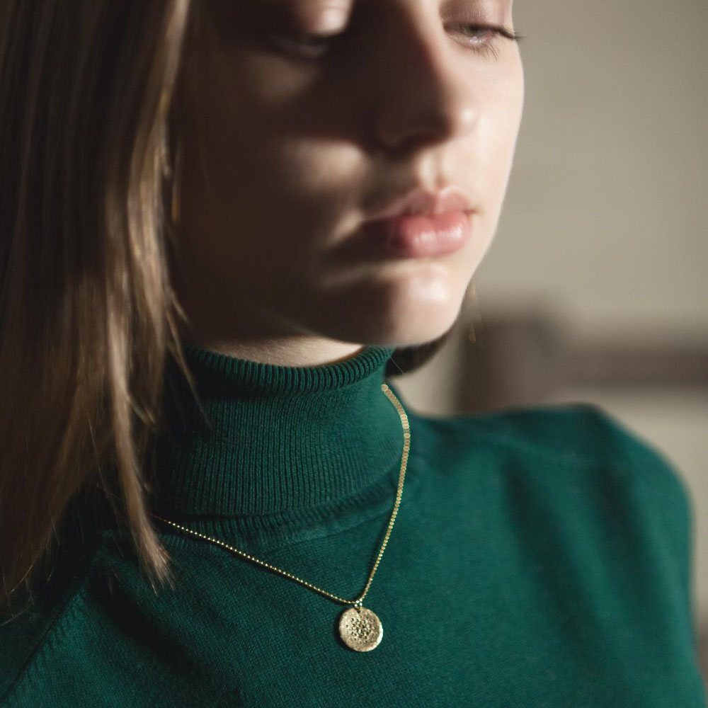 לקוחה של תכשיטי ים אור עם שרשרת ותליון זהב על חולצת גולף ירוקה